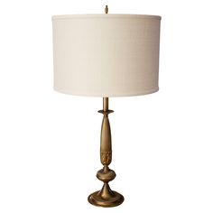 a gold table lamp with a white shade on the base and a beige linen lampshade