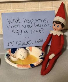 an elf is sitting next to a sign that says, what happens when you're on egg a joke? it cracks up