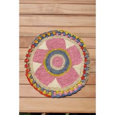 a pink and white crocheted doily on wooden planks