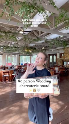 a woman is standing in the middle of a room holding a sign that says, 80 person wedding character board