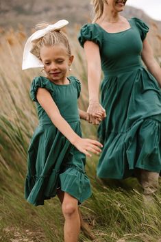 Welcome autumn in style with the Dahlia Dress in Green. This darling piece features a scoop neckline and short puff sleeves with elastic closures for a sweet & comfortable fit. The midi-length skirt with functional pockets and a ruffle tier hem adds just the right touch of seasonal charm to your wardrobe. coastal cowgirl, smocked bodice, beach photoshoot, mommy & me, summer dress, fall dress, rock, coastal aesthetic, midi dress, date night outfit, outfit inspiration, green, puffed sleeve Green Puff Sleeve Dress With Ruffles, Casual Tiered Dress With Short Sleeves, Casual Solid Color Short Sleeve Tiered Dress, Solid Color Dresses With Ruffle Hem And Flutter Sleeves, Casual Midi Dress With Ruffled Skirt, Modest Flutter Sleeve Dress With Ruffle Hem, Modest Dress With Ruffle Hem And Flutter Sleeves, Casual Tiered Ruffle Dress With Puff Sleeves, Modest Dress With Flutter Sleeves And Ruffle Hem