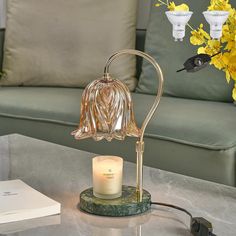 a glass table with a candle and some flowers on top of it next to a couch