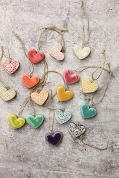 heart shaped ceramic ornaments hanging from twine on concrete surface with string attached to them