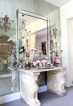 a room with a mirror, vases and chandelier on the wall next to it