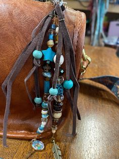 a brown leather purse sitting on top of a wooden table covered in beads and charms