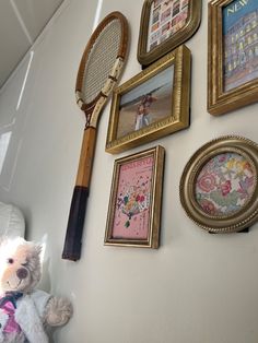 a teddy bear is sitting next to some framed pictures and tennis rackets on the wall