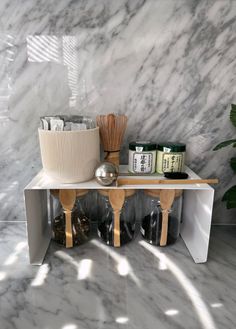 a marble counter top with wooden utensils and other kitchen items sitting on it