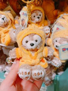 a person holding a teddy bear keychain in front of other stuffed animals on display