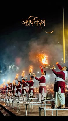 a group of men in red and white outfits holding torches on top of a stage