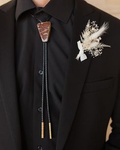 a man in a black suit with a white flower and feather lapel pin on his lapel