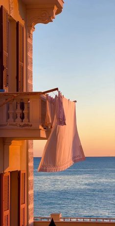 clothes hanging out to dry in front of an ocean view at sunset with the sun setting