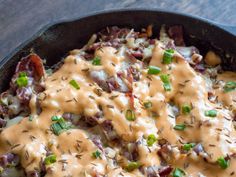 a skillet filled with potatoes covered in gravy and topped with green onions