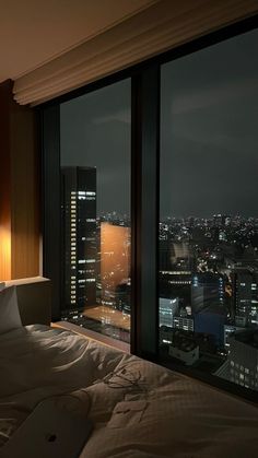 a bedroom with a view of the city at night