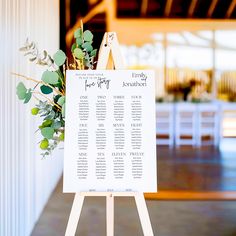 an easel with seating cards and greenery on it