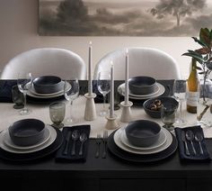 the table is set with black and white plates, silverware, and candlesticks