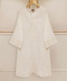 Designer White Blouse For Eid, Transitional White Salwar Kameez With Floral Embroidery, White Salwar Kameez With Floral Embroidery For Transitional Seasons, Spring Designer White Kurta, White Designer Kurta For Spring, Elegant Off White Cotton Kurta, White Traditional Wear With Naqshi Embroidery, White Traditional Wear With Naqshi On Straight Kurta, Embroidered White Cambric Traditional Wear