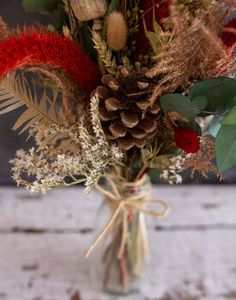 a vase filled with flowers and pine cones