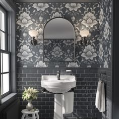 a white sink sitting under a bathroom mirror next to a window with flowers on it