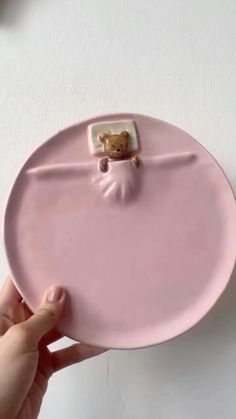 a person holding a pink plate with a teddy bear on the front and bottom part