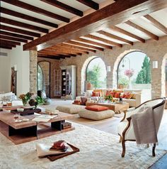 a living room filled with lots of furniture and large arched windows in the middle of it