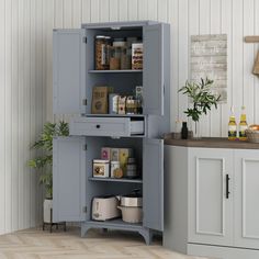 an open cabinet in the corner of a room with white walls and wood flooring