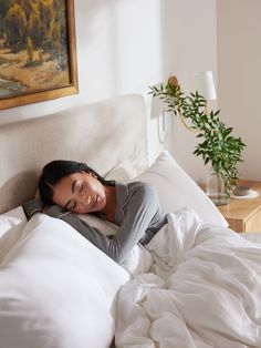 a woman is laying in bed with her head on the pillow and smiling at the camera