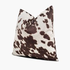 a brown and white cow print pillow on a white background