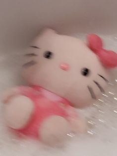 a hello kitty toy laying in the bathtub with bubbles on it's side