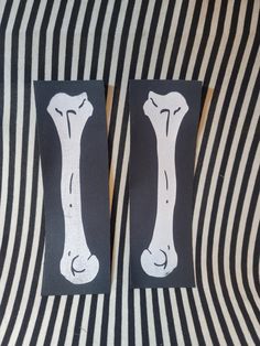 two pieces of paper with black and white stripes on them, one has a drawing of a bone