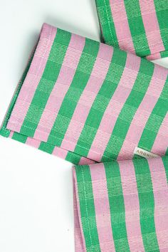 the pink and green striped scarf is folded on top of another piece of cloth,