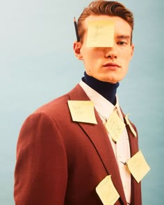 a man with sticky notes on his face and neck, standing in front of a blue background