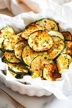 a white bowl filled with zucchini and cheese on top of a marble counter