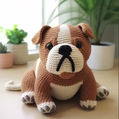 a brown and white stuffed dog sitting on top of a table next to a potted plant