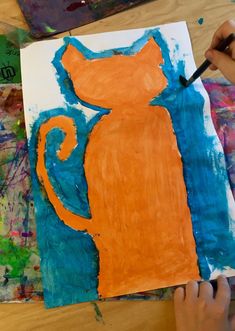 someone is painting an orange cat on a piece of paper with blue and orange paint