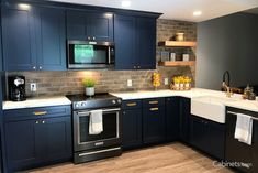 a kitchen with dark blue cabinets and white counter tops is pictured in this image, there are towels hanging on the sink