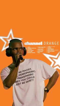 a man with headphones on standing in front of an orange background