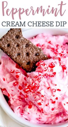 a white bowl filled with cream cheese dip and topped with crackers, pomegranates