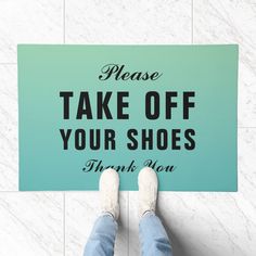 a person standing on the floor with a sign that says please take off your shoes thank you