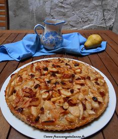 a pie sitting on top of a white plate next to a blue and white pitcher