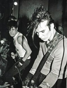 black and white photograph of two men playing guitar in front of a group of people