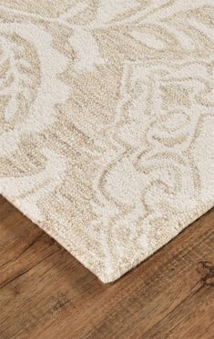 an area rug on top of a wooden floor with a white and beige color scheme