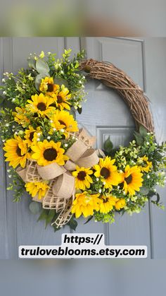 a wreath with sunflowers and greenery on the front door