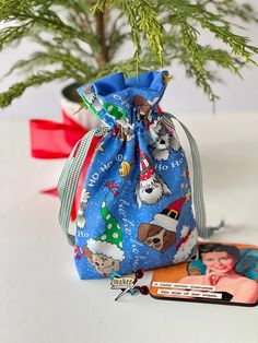 a small christmas tree in a blue bag next to some cards and a pair of scissors