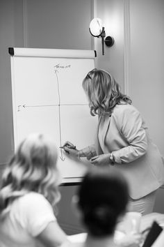 a woman standing in front of a white board