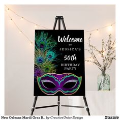 a welcome sign with a purple mask and peacock feathers in front of a string of lights