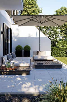 an outdoor living area with couches, tables and umbrellas on the side of it