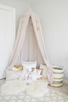 a pink canopy bed in a girls'bedroom with white walls and gold stars on the ceiling