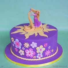 there is a purple cake decorated with flowers and a girl on top that has long blonde hair