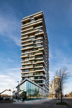 a very tall building with lots of windows on the top and bottom floor, next to a street