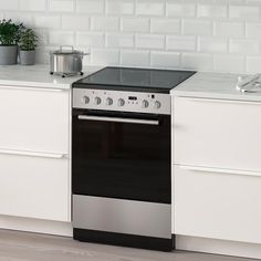 a stove top oven sitting inside of a kitchen next to white cupboards and drawers